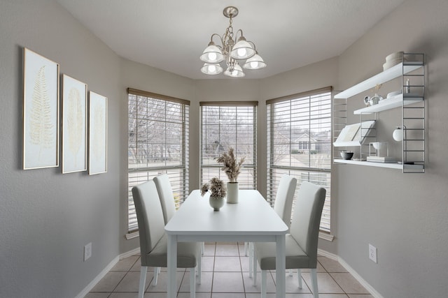 dining area with light tile patterned floors, baseboards, and an inviting chandelier