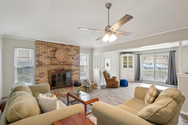 living area with plenty of natural light, a fireplace, wood finished floors, and crown molding