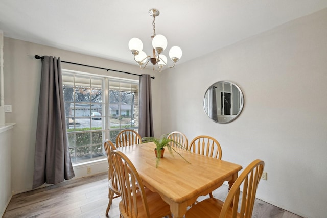 dining area with light wood-style flooring and a notable chandelier