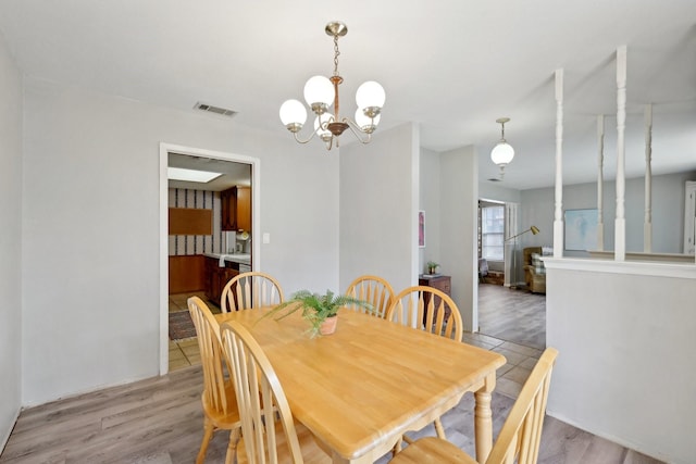 dining space featuring light wood-style floors, visible vents, and a notable chandelier