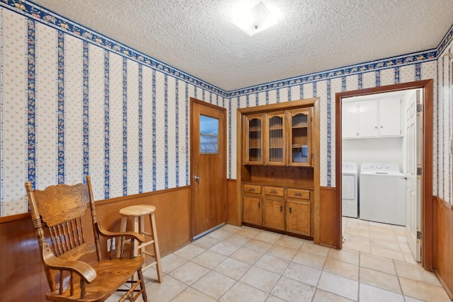 sitting room featuring a wainscoted wall, light tile patterned floors, a textured ceiling, separate washer and dryer, and wallpapered walls