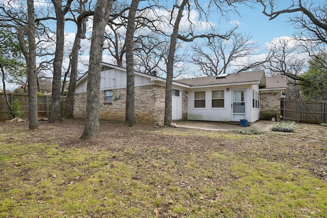 exterior space with brick siding, board and batten siding, a patio area, and fence