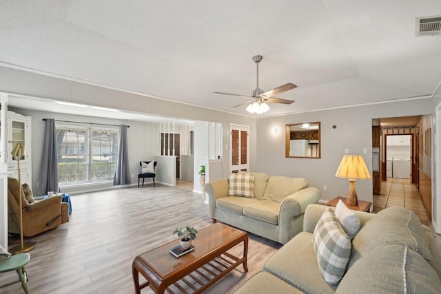 living area featuring light wood-style flooring, visible vents, and ceiling fan