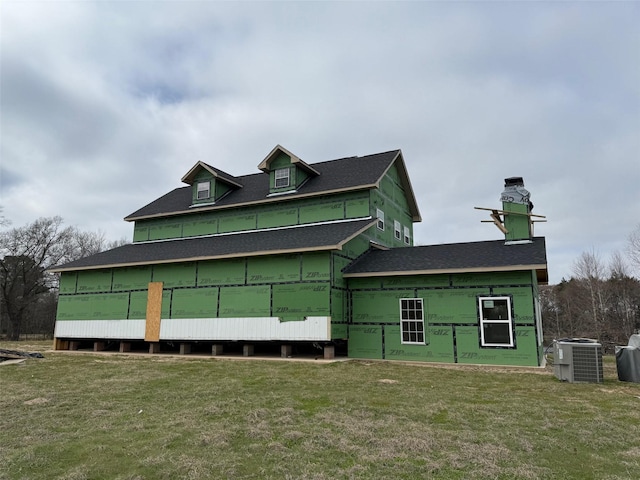 view of side of home with central AC unit and a lawn