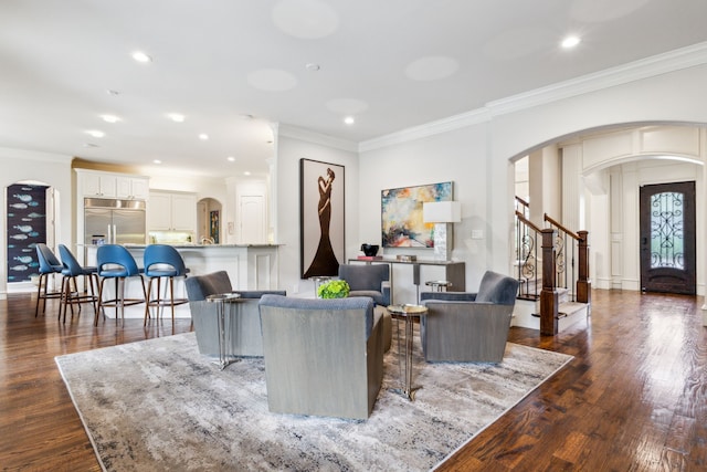 living room with crown molding, arched walkways, and dark wood finished floors