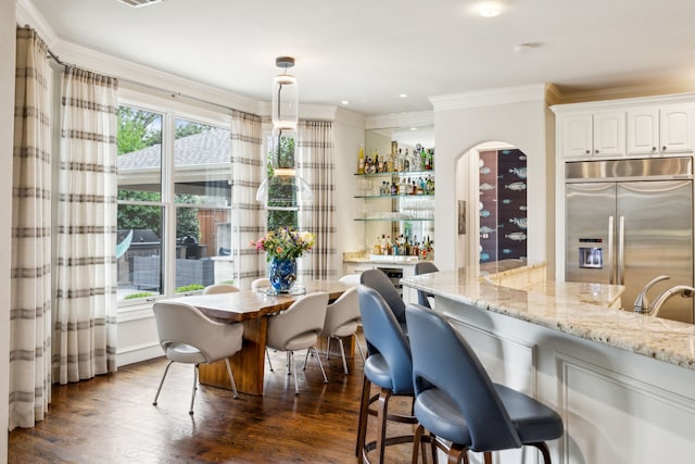 kitchen with dark wood-type flooring, ornamental molding, white cabinetry, light stone countertops, and stainless steel built in refrigerator