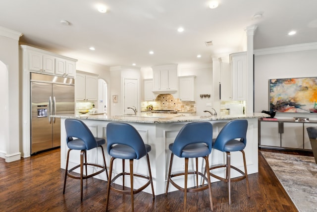 kitchen featuring light stone counters, dark wood-style flooring, white cabinetry, and stainless steel built in fridge