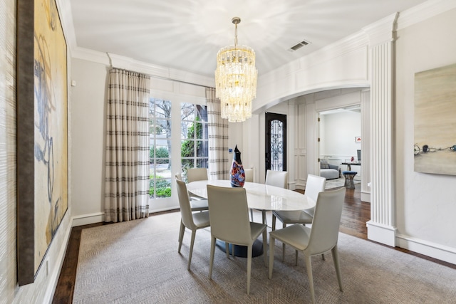 dining space featuring arched walkways, a notable chandelier, wood finished floors, visible vents, and ornamental molding