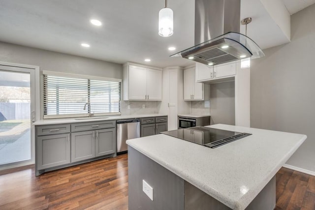 kitchen featuring island range hood, black electric stovetop, stainless steel dishwasher, pendant lighting, and a sink