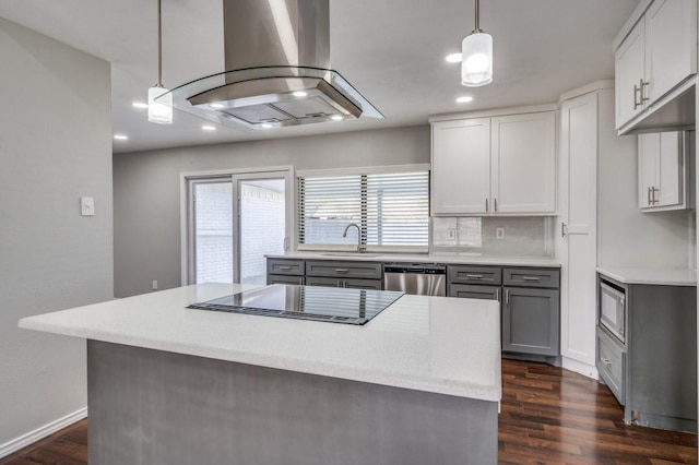 kitchen with light countertops, hanging light fixtures, stainless steel appliances, and island range hood