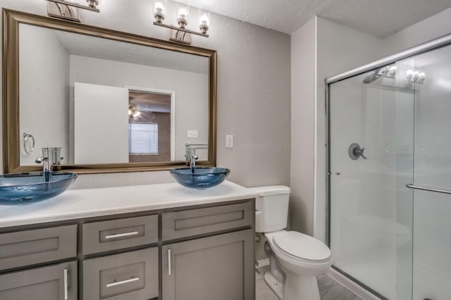 bathroom with a textured wall, toilet, a textured ceiling, vanity, and a shower stall