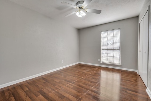 spare room with ceiling fan, baseboards, and dark wood-style flooring