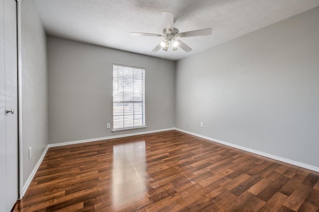 spare room with dark wood-style flooring, ceiling fan, a textured ceiling, and baseboards