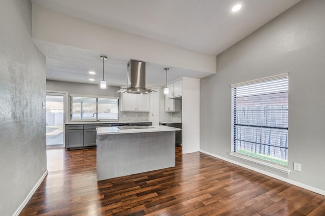 kitchen featuring hanging light fixtures, light countertops, a center island, dark wood-style floors, and island exhaust hood