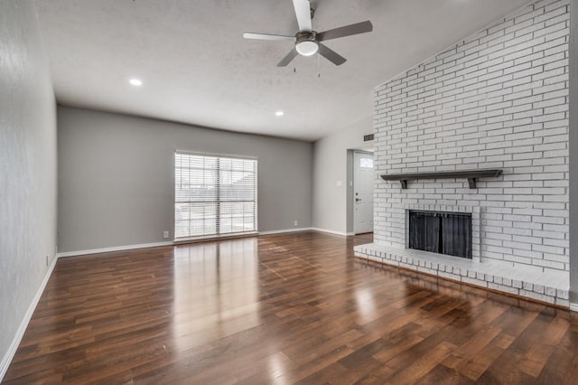 unfurnished living room with dark wood-type flooring, visible vents, a ceiling fan, baseboards, and a brick fireplace