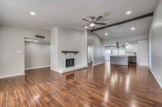 unfurnished living room featuring baseboards, lofted ceiling with beams, ceiling fan, dark wood-style flooring, and a brick fireplace