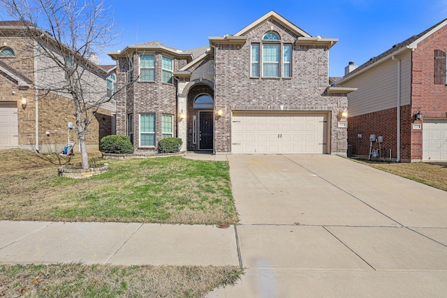 traditional-style house with an attached garage, a front yard, concrete driveway, and brick siding