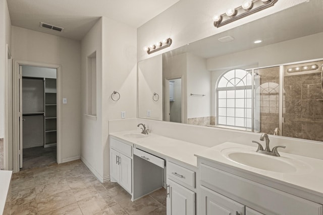 bathroom with a sink, visible vents, a spacious closet, double vanity, and a stall shower