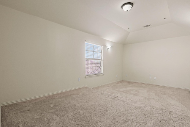 spare room with lofted ceiling, baseboards, visible vents, and light colored carpet