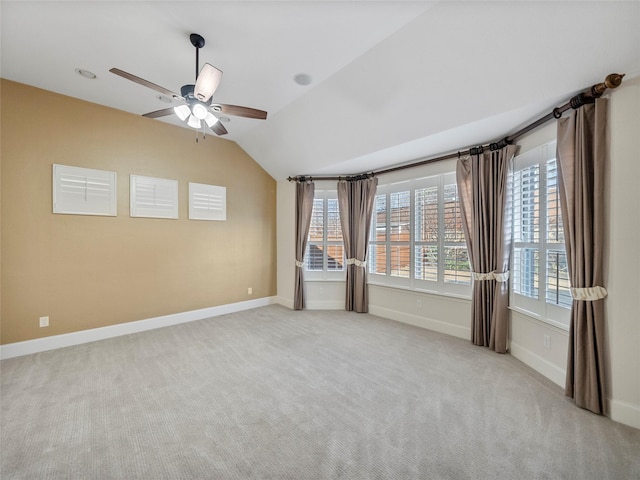 empty room featuring baseboards, lofted ceiling, and light colored carpet