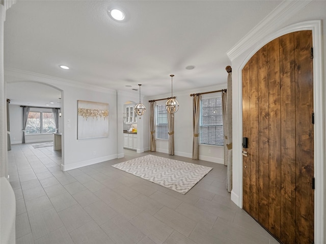 entryway with recessed lighting, baseboards, arched walkways, and ornamental molding