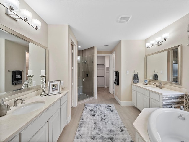 bathroom featuring a stall shower, a garden tub, two vanities, and a sink