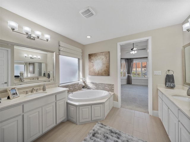 bathroom with two vanities, visible vents, a sink, and a bath