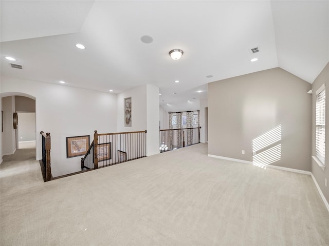 empty room with vaulted ceiling, visible vents, arched walkways, and recessed lighting