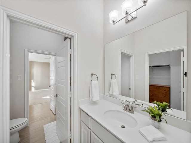 bathroom featuring toilet, wood finished floors, and vanity