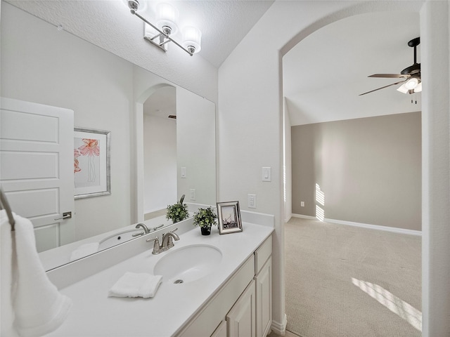 bathroom featuring ceiling fan, lofted ceiling, vanity, and baseboards