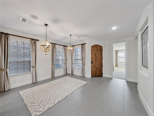 empty room with arched walkways, baseboards, visible vents, and crown molding