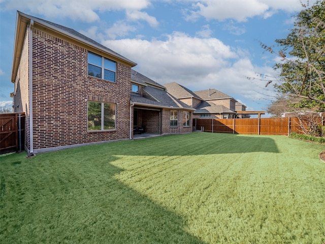 back of property featuring a yard, brick siding, and a fenced backyard