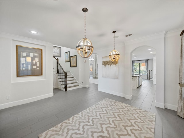 foyer entrance featuring baseboards, visible vents, arched walkways, stairs, and crown molding