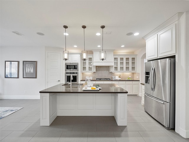 kitchen featuring glass insert cabinets, stainless steel appliances, white cabinetry, dark countertops, and decorative light fixtures