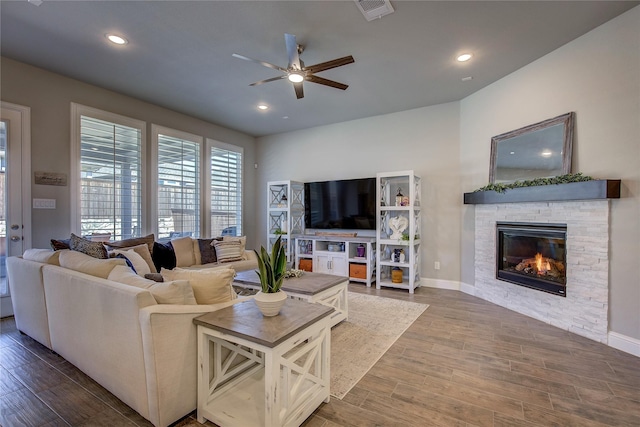 living area featuring a stone fireplace, recessed lighting, wood finished floors, visible vents, and baseboards