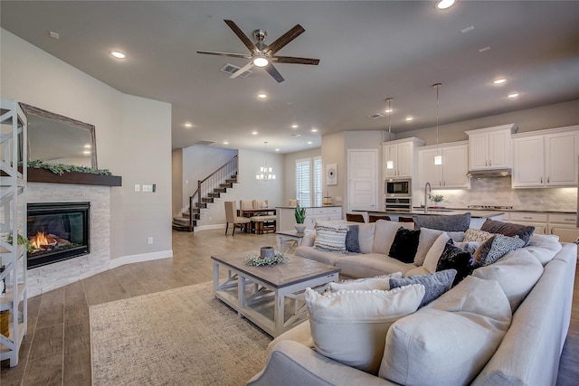 living area with light wood finished floors, visible vents, stairs, a fireplace, and recessed lighting