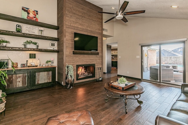 living room with a fireplace, a ceiling fan, dark wood-type flooring, and a textured ceiling