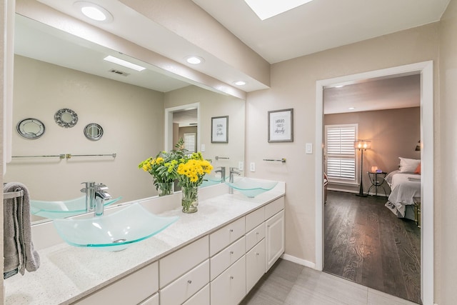 full bath featuring ensuite bathroom, double vanity, a sink, and recessed lighting