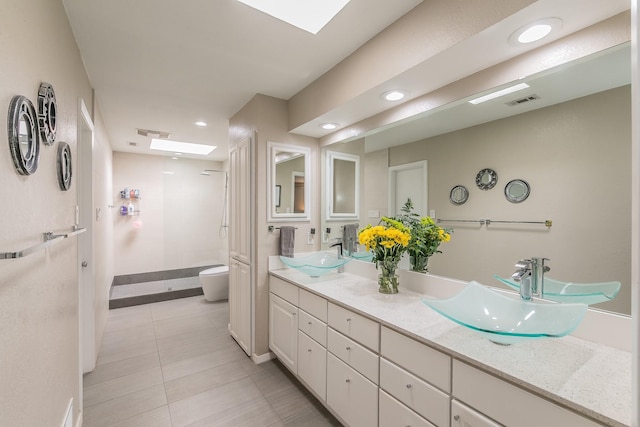 bathroom with toilet, double vanity, a sink, and tile patterned floors