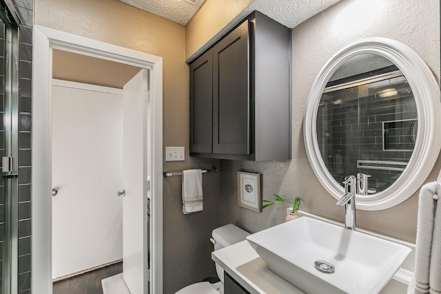 bathroom with a textured wall, vanity, and toilet