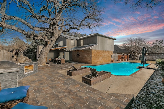 view of swimming pool with a patio area, an outdoor kitchen, a fenced backyard, and a fenced in pool