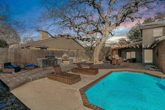 pool at dusk featuring a patio, a fenced backyard, exterior kitchen, grilling area, and a fenced in pool