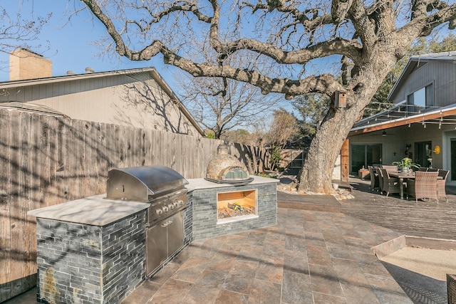 view of patio / terrace featuring outdoor dining space, an outdoor kitchen, a fenced backyard, and a grill