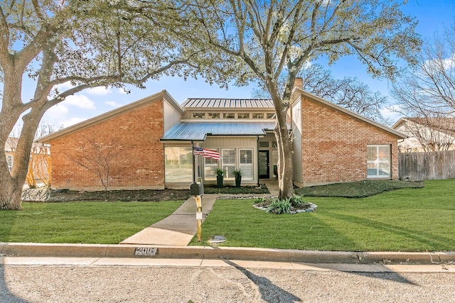 exterior space featuring fence, a front lawn, and brick siding