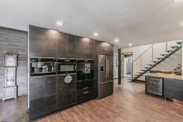 kitchen with high end refrigerator, modern cabinets, wine cooler, wood finished floors, and oven