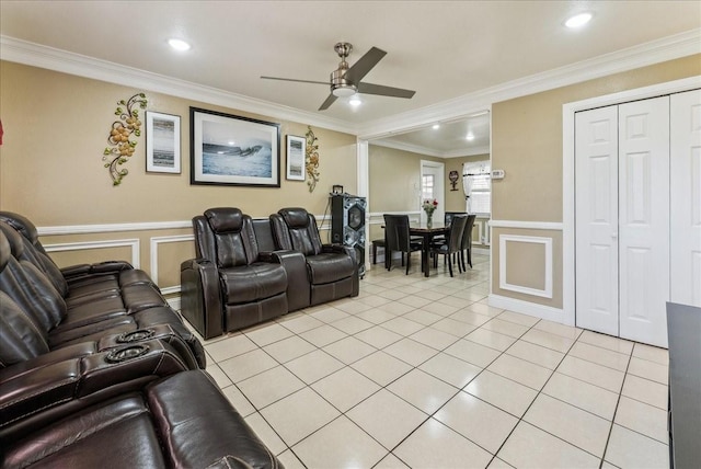 living area with crown molding, light tile patterned floors, a decorative wall, wainscoting, and ceiling fan