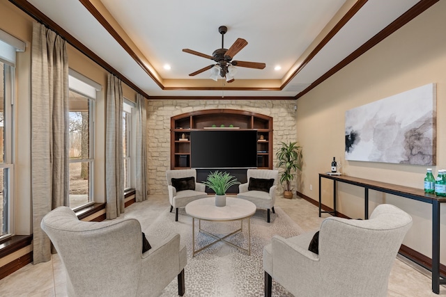 living room with baseboards, a tray ceiling, a ceiling fan, and a healthy amount of sunlight