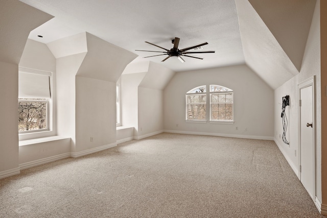 bonus room featuring light carpet, baseboards, a ceiling fan, vaulted ceiling, and a textured ceiling