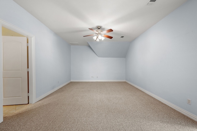 additional living space with a ceiling fan, lofted ceiling, visible vents, and light carpet