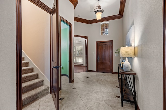 foyer with ornamental molding, light tile patterned flooring, and baseboards